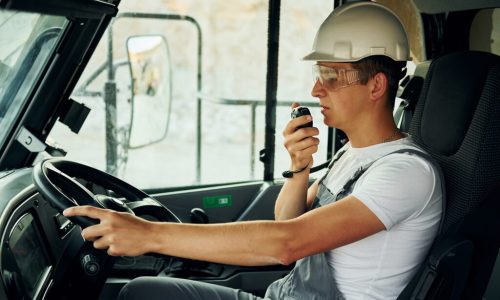 Driving transport. Worker in professional uniform is on the borrow pit at daytime.